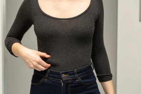 Close-up view of a lady squeezing the fat above her jeans 스톡 사진