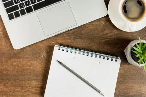 Close-up view of laptop, blank notebook and cup of coffee on wooden table top 库存照片