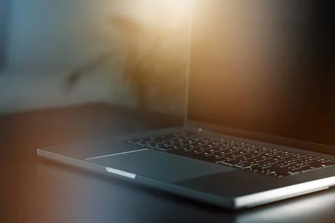 Close view of a laptop on a dark table with a soft light around it showing the Stock Photos