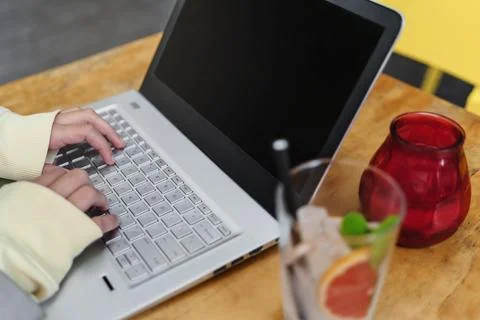 Close-up view on laptop screen while woman typing info with keyboard sitting in Stock Photos