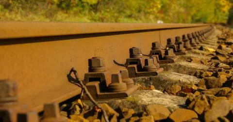A close-up view of the large screws securing the train tracks during a sunny  Фото