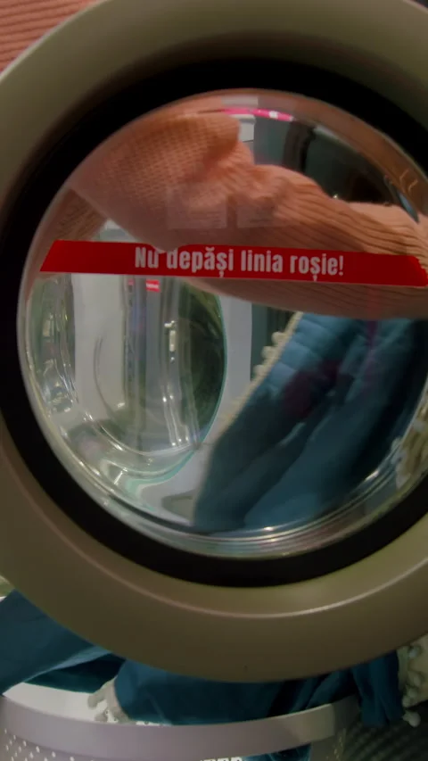 Close-up view of laundry being loaded into a washing machine with visible Stock Footage 330020568