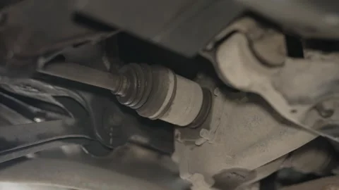 A close-up view of a leaking or damaged rubber CV joint boot on a car axle. Stock Footage 340978124