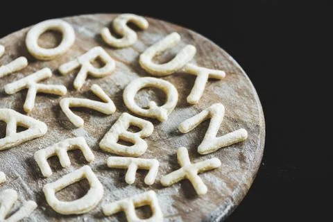 Close up view of letters made from cookie dough on wooden board with flour is Foto stock