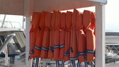 Close view of life jackets with moored boats in soft background light, blending Stock Footage 318294013