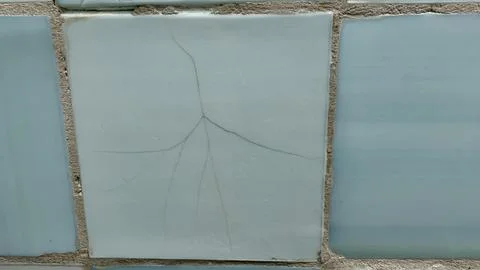 A close-up view of a light blue ceramic tile shows a prominent crack extending Stock Photos