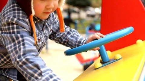 Close-up view of little boy hands driving big toy car helm outside on modern Video stock 118690749