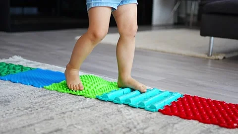 Close up view of Little girl walks on a massage mat. Toddler baby foot massage Stock Footage