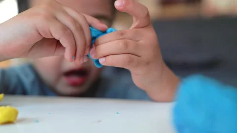 Close-up view of little hands of a boy playing with blue and yellow clay on the Stock Footage 194855104