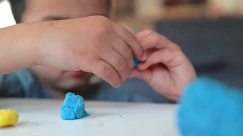 Close-up view of little hands of a boy playing with blue and yellow clay on the Video stock 194855539