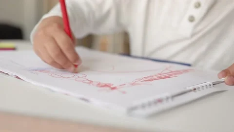 Close-up view of little hands drawing with red pen on a white paper. Stock Footage 194332285