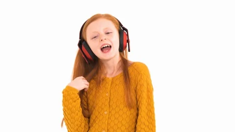 Close-up view of a little red haired girl listening to the music in wireless Stock Footage 121782617