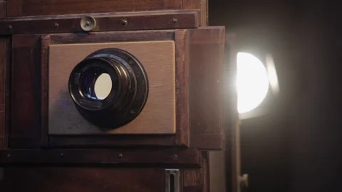 Close-up view of luminous lens of outdated rare wooden accordion camera in dark 库存影片 133085582