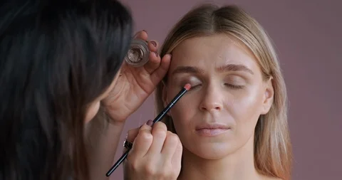Close-up view of make-up artist’s hand applying eye shadow brush woman Stock Footage 120149521