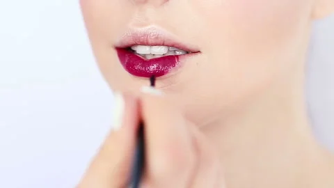 Close up view of a makeup artist applying lipstick on model's lips. Stock Footage 125614623