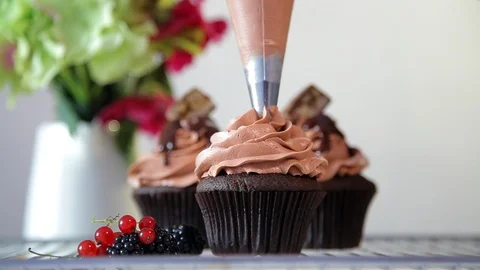 Close up view of making cream top on the chocolate cupcake using pastry bag. Stock Footage 102932104