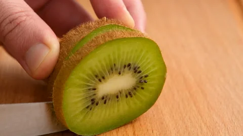 Close-up view of male hands cutting kiwi fruits on the kitchen table Stock Footage 273035448