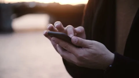 Close-up view of male hands holding the smartphone and typing on touchscreen Stock Footage