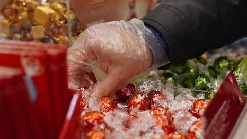 Close up view of male hands selecting some chocolate bonbons in the supermarket Stock Footage