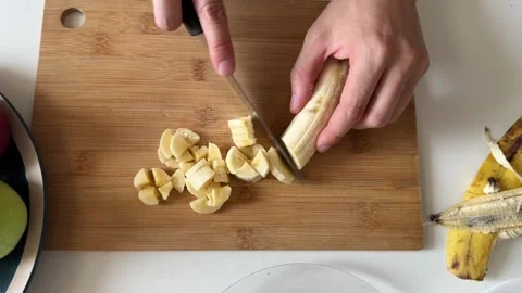 Close-up view of male hands slicing banana on cutting board. Homemade fruit Stock Footage 337339128