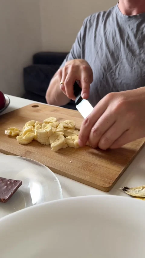 Close-up view of male hands slicing banana on cutting board. Homemade fruit Stock Footage 337358377
