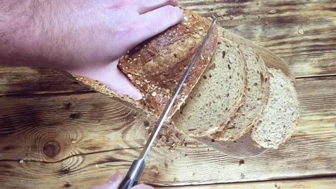 Close up view. Man cuts bread into slices on wooden cutting board Stock Footage 123352224
