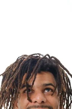 Close up view of a man with dreadlocks looking up while standing against a white Stock Photos