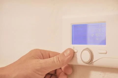 Close up view of man hand adjusting temperature on modern wall electronic d.. 库存照片
