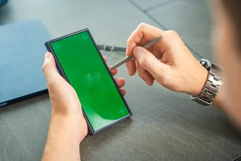 Close up view of man hand holding smart phone with green chroma key screen and Stock Photos
