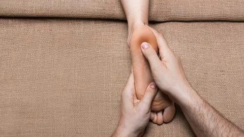 Close up view of a man hands massaging woman's feet on canvas in spa salon Stock Photos