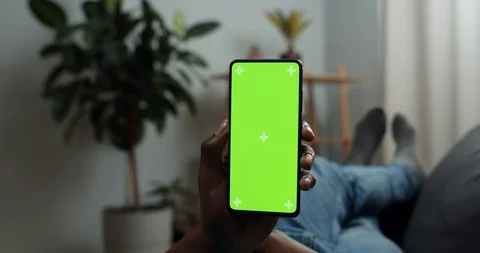 Close up view of man holding smartphone with mock up screen while lying on sofa Stock Footage 129492444