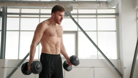 Close-up view of a man lifting heavy kettlebells towards his chest Stock Footage 227777261