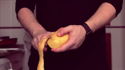 Close-up view of a man peeling a potato in his home kitchen. Stock Footage 169078923