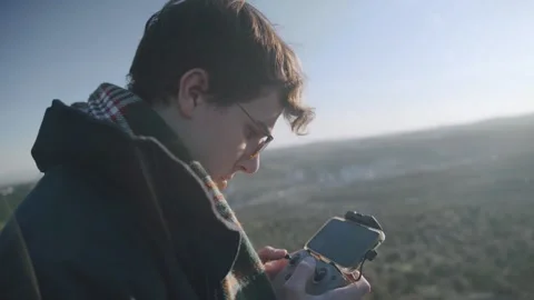 A close-up view of a man piloting his drone with a remote control connected.. Stock Footage 240397657