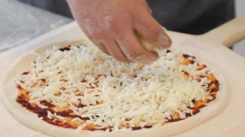 Close up view of a man preparing an italian pizza, sprinkling fresh cheese  스톡 동영상 137530950