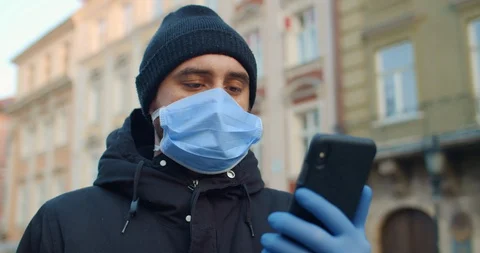 Close up view of man in protective mask and gloves looking at phone screen. Guy Video stock 127574832