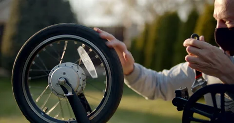 Close up view of a man in protective mask repairing wheel of a bike Stock Footage 138822187
