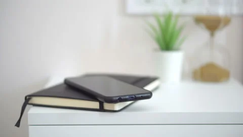 Close-up view of Man put smartphone to notebook Stock Footage 155980033