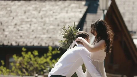 The close-up view of the man raising up the smiling woman with the bouquet and Stock Footage 75678959