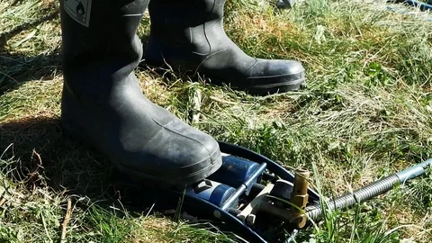 Close up view of a man in rubber boots pumping via pump. Agriculture, taking Video stock 99361486