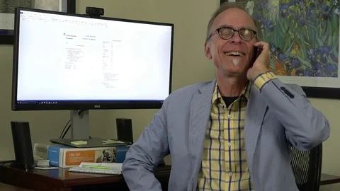 A close-up view of a man siting in home office chair, talking on cell phone, Stock-Footage 78882334