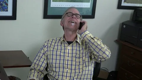 A close-up view of a man siting in home office chair, talking on cell phone, Stock-Footage 78882338