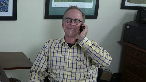 A close-up view of a man siting in home office chair, talking on cell phone, Stock-Footage 78882341