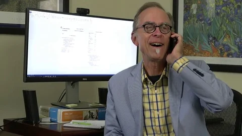 A close-up view of a man siting in home office chair, talking on cell phone, Stock-Footage 79110989