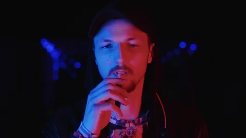 Close up view of a man smoking a cigarette and letting out smoke in a nightclub Stock Footage 111221119