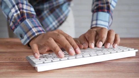 Close up view of man typing on white wireless computer keyboard at wooden d.. Stock Footage 333153274