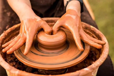 Close-up view of man working on pottery wheel and making clay pot outdoor Stock Photos