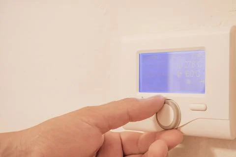 Close up view of mans hand adjusting digital thermostat controller dial on .. Stock Photos
