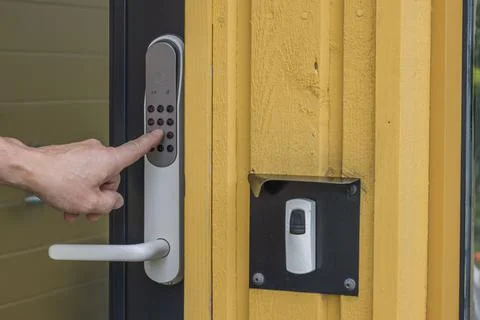 Close up view of man's hand dialing code on digital lock of entrance door. Stock Photos