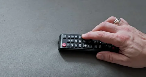 Close-up view of a man's hand pressing a button on a TV remote control. Stock Footage 246717618